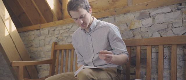 a 博天堂官方入口登陆登录 student sitting 和 writing on a notepad.